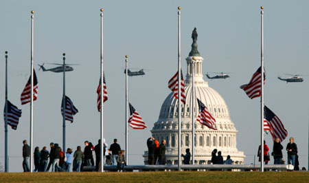 Flags fly at half staff in memory of former U.S. President Gerald Ford at the Washington Monument as military helicopters pass over the dome of the Capitol in Washington December 27, 2006. Ford, the 38th U.S. President, died at his home in California on Tuesday at age 93. Ford's body will lie in state for a period of public mourning in the Capitol Rotunda beginning this weekend.